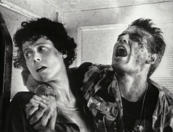 A screenshot from the movie Aliens in greyscale. Ripley is helping an injured Corporal Hicks walk. His chest and face are sprayed with burning acid, much like that of the acid ants' spit attack.
